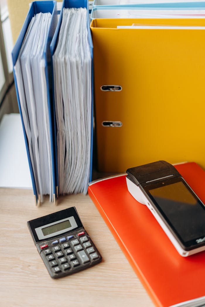 Organized office desk with a calculator, files, and documents for efficient work.